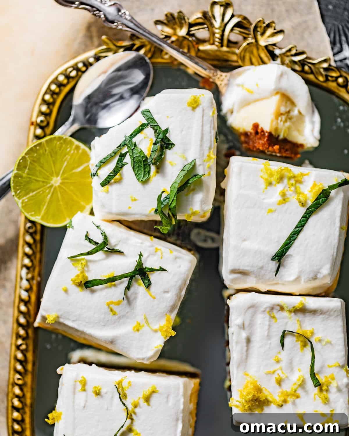 An inviting overhead view of beautifully arranged key lime pie bars on a sophisticated serving tray, each topped with a dollop of cream and lime zest, ready to be enjoyed.