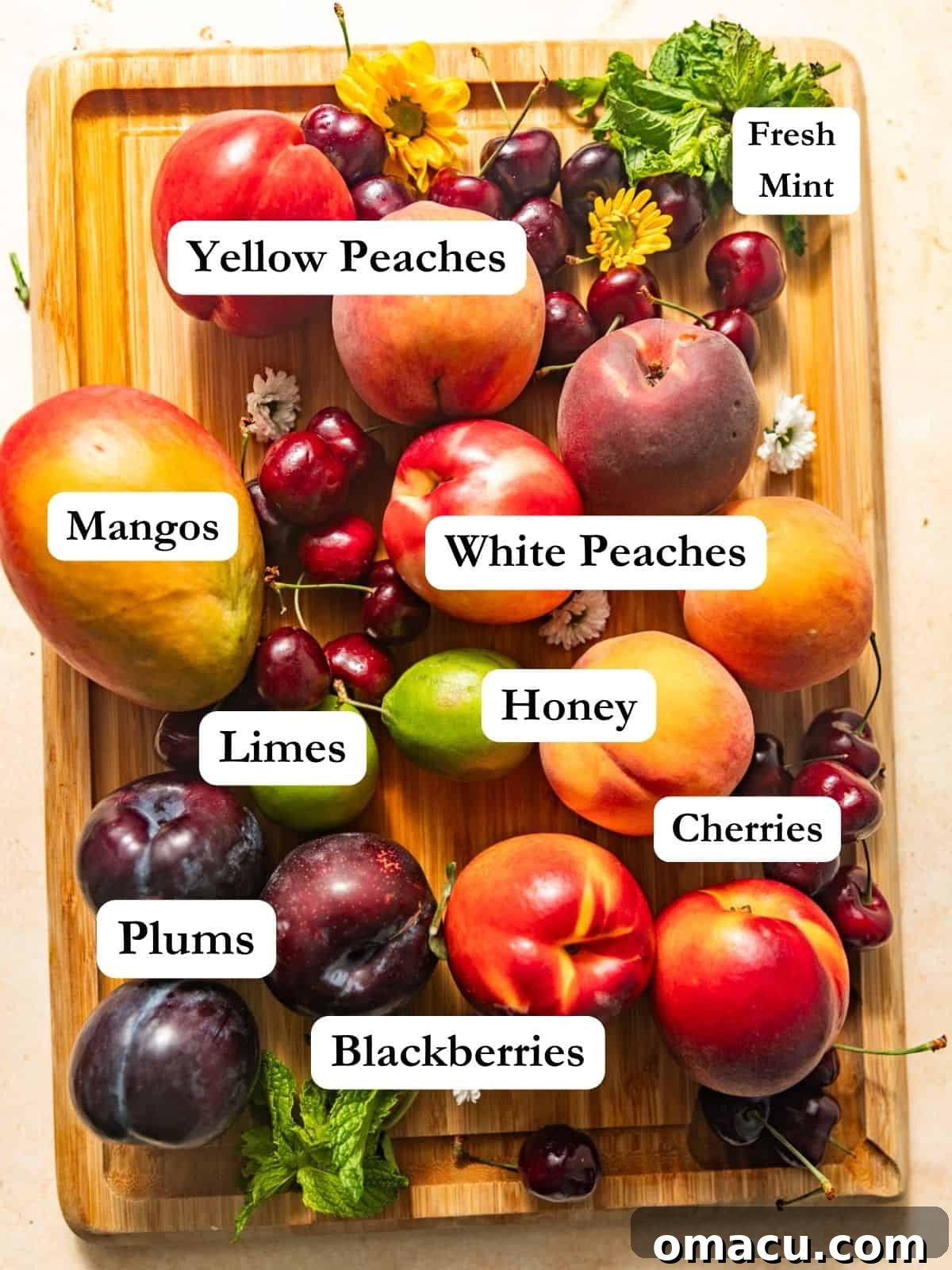 A vibrant selection of fresh ingredients laid out on a wooden surface for making stone fruit salad, featuring sliced yellow peaches, white peaches, plums, ripe red cherries, sweet orange mangoes, fresh green mint, golden honey, and zesty green limes, alongside a handful of glossy black blackberries.