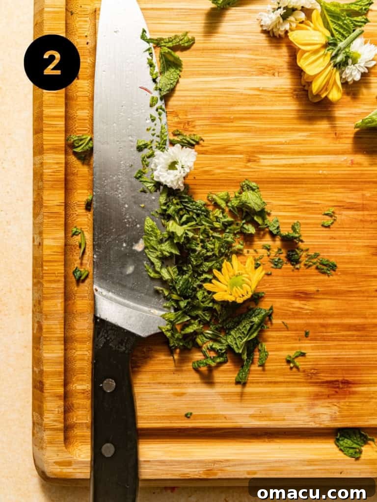 Finely chopped fresh mint leaves and vibrant grated lime zest are neatly presented on a clean wooden cutting board, prepped and ready to be mixed into the fruit salad.