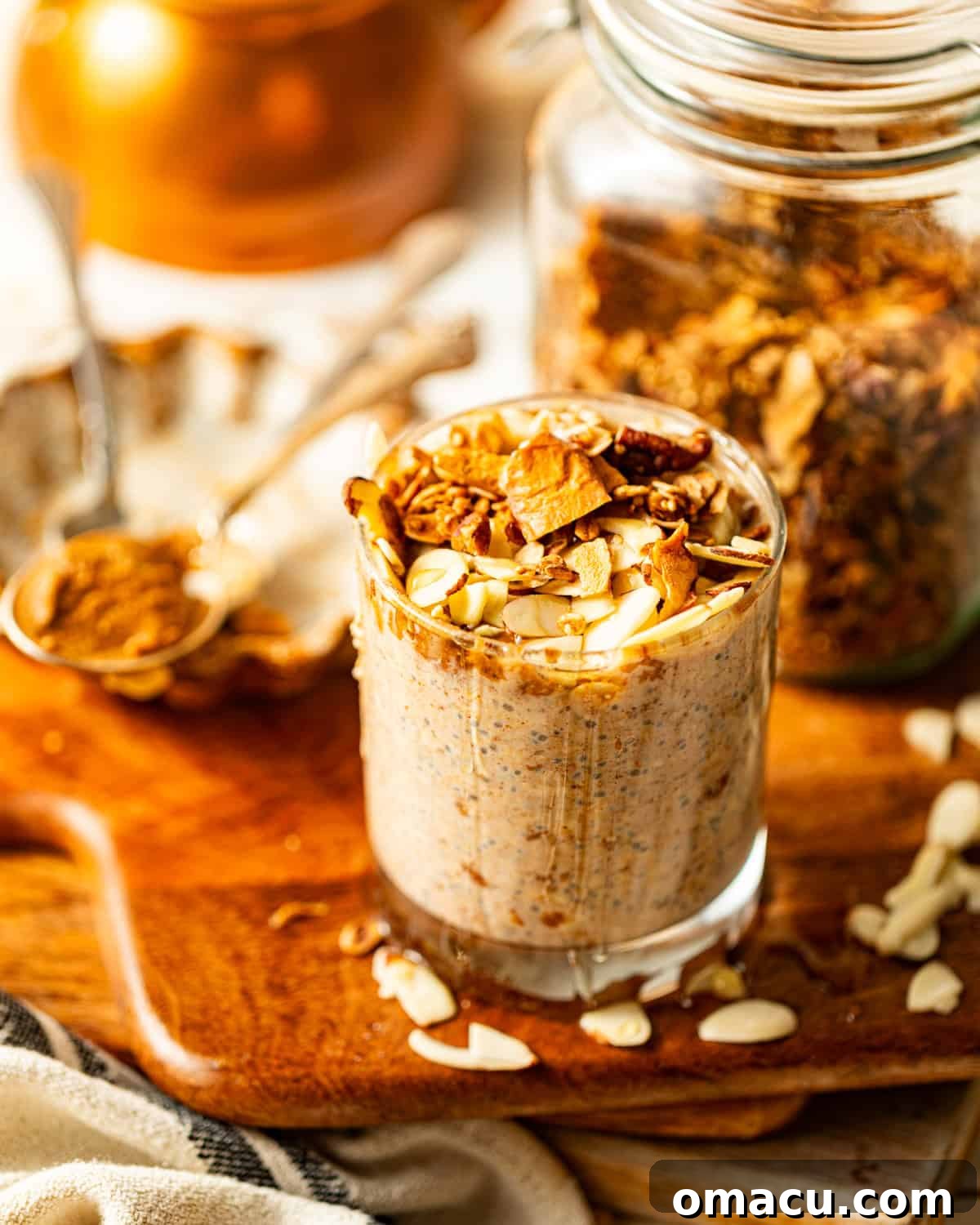 Creamy almond butter overnight oats in a glass jar, garnished with sliced almonds and a drizzle of almond butter, sitting on a rustic serving board, ready for a delicious and healthy breakfast.