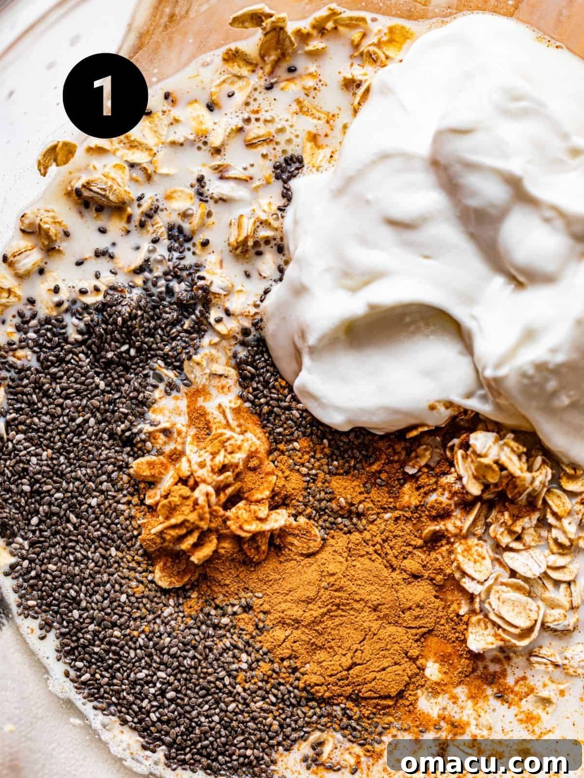 A large mixing bowl filled with milk, Greek yogurt, chia seeds, vanilla extract, and cinnamon, perfectly combined and ready for the next step of making almond butter overnight oats.