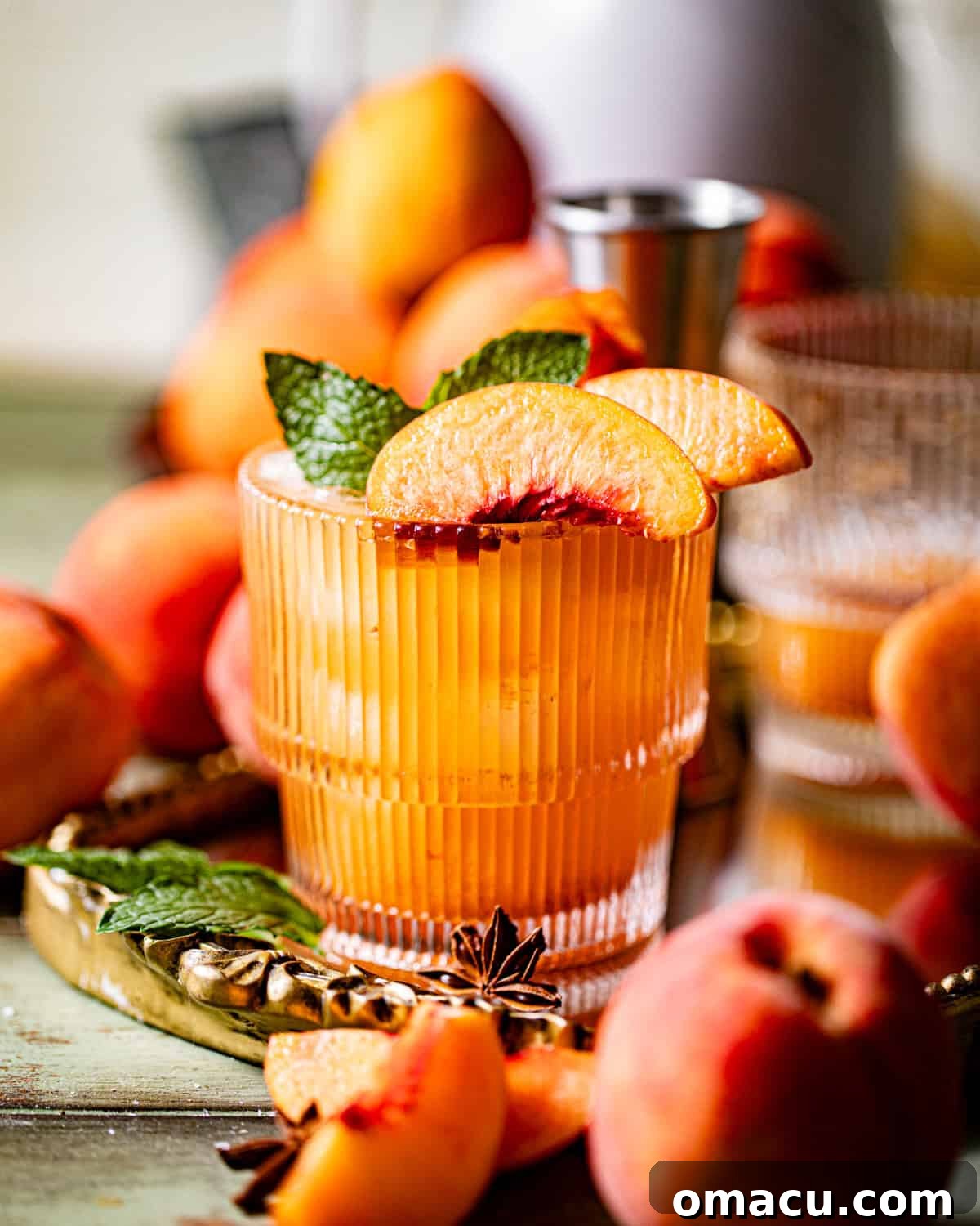 A vibrant peach bourbon cocktail in a sophisticated glass, garnished with fresh mint leaves and thin peach slices, capturing the essence of a perfect summer drink.