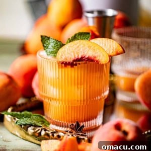 A perfectly mixed peach bourbon cocktail in a glass, garnished with fresh mint and peach slices, showcasing its refreshing appeal.