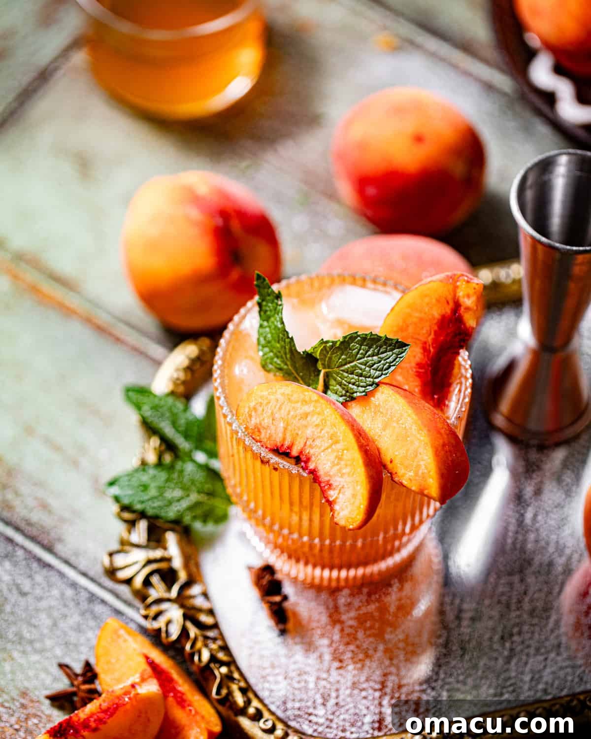 A single glass of peach bourbon cocktail elegantly placed on a reflective mirror tray, showcasing its rich color and inviting texture.