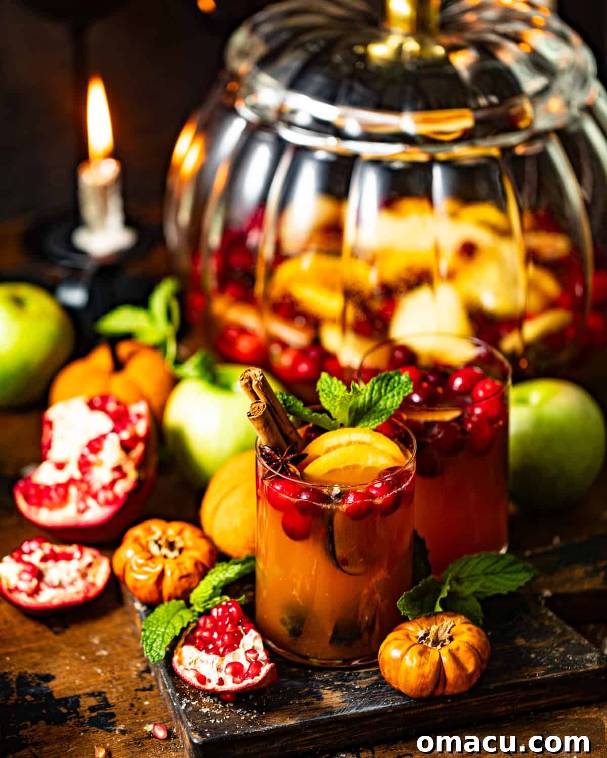 autumn sangria in a glass in front of a pitcher filled with sangria.