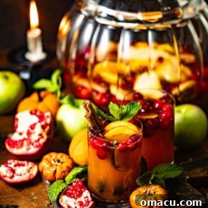 autumn sangria in a glass in front of a pitcher filled with sangria.