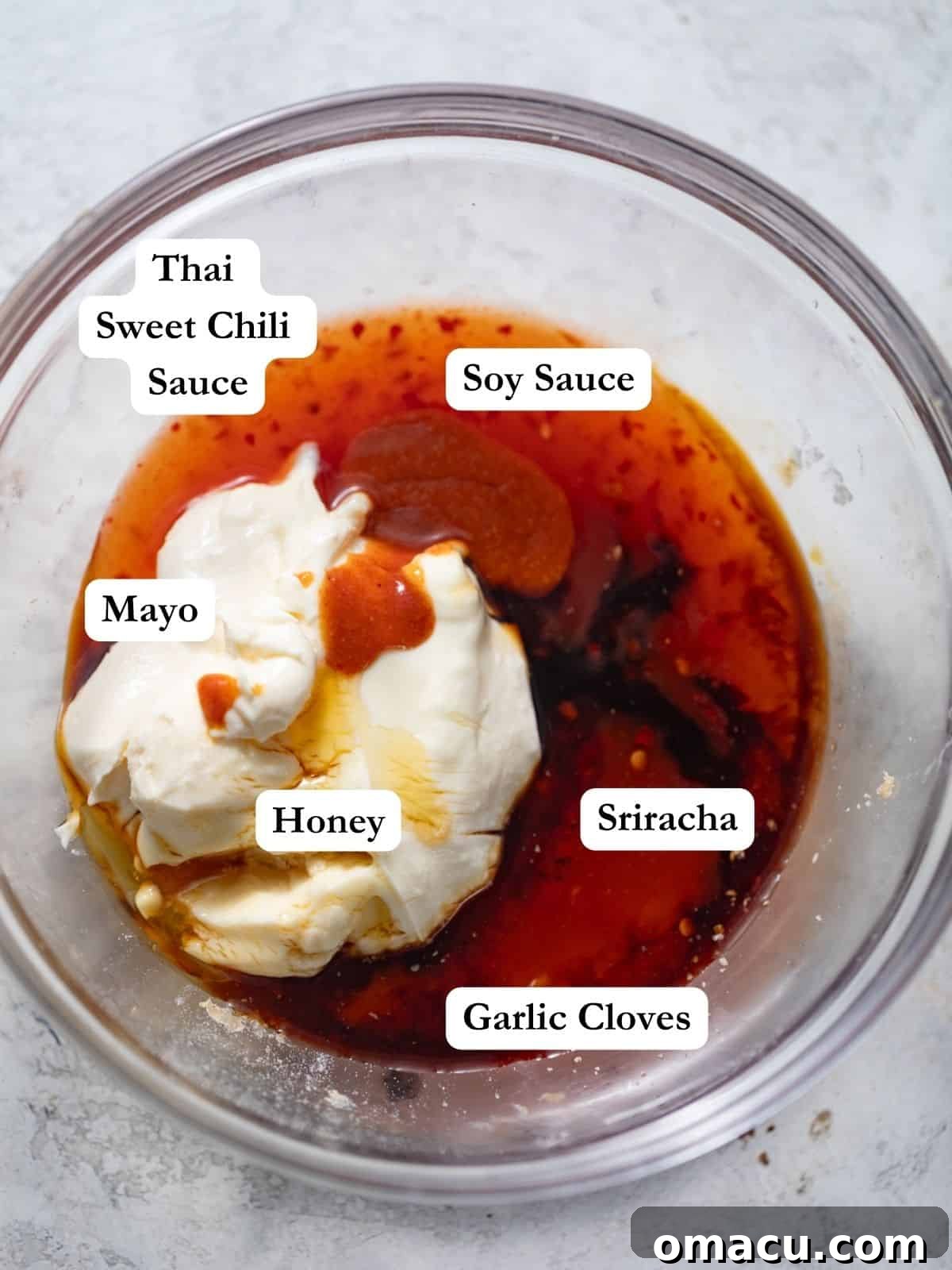 A selection of ingredients for Bang Bang sauce displayed in a bowl: sriracha, sweet Thai chili sauce, mayonnaise, honey, and minced garlic, ready to be combined.