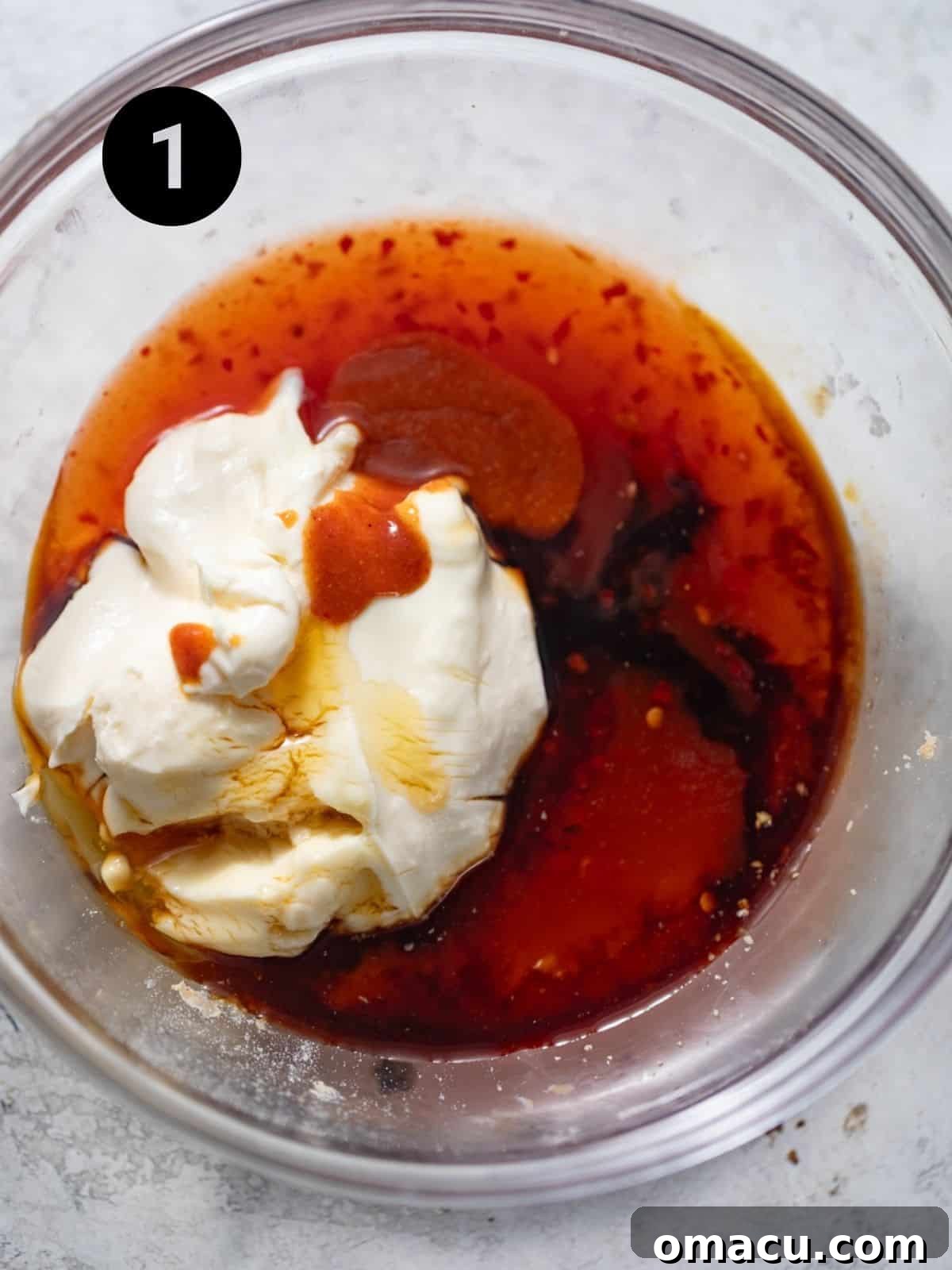 Ingredients for Bang Bang sauce being combined in a bowl, showcasing the creamy texture and vibrant colors before whisking.