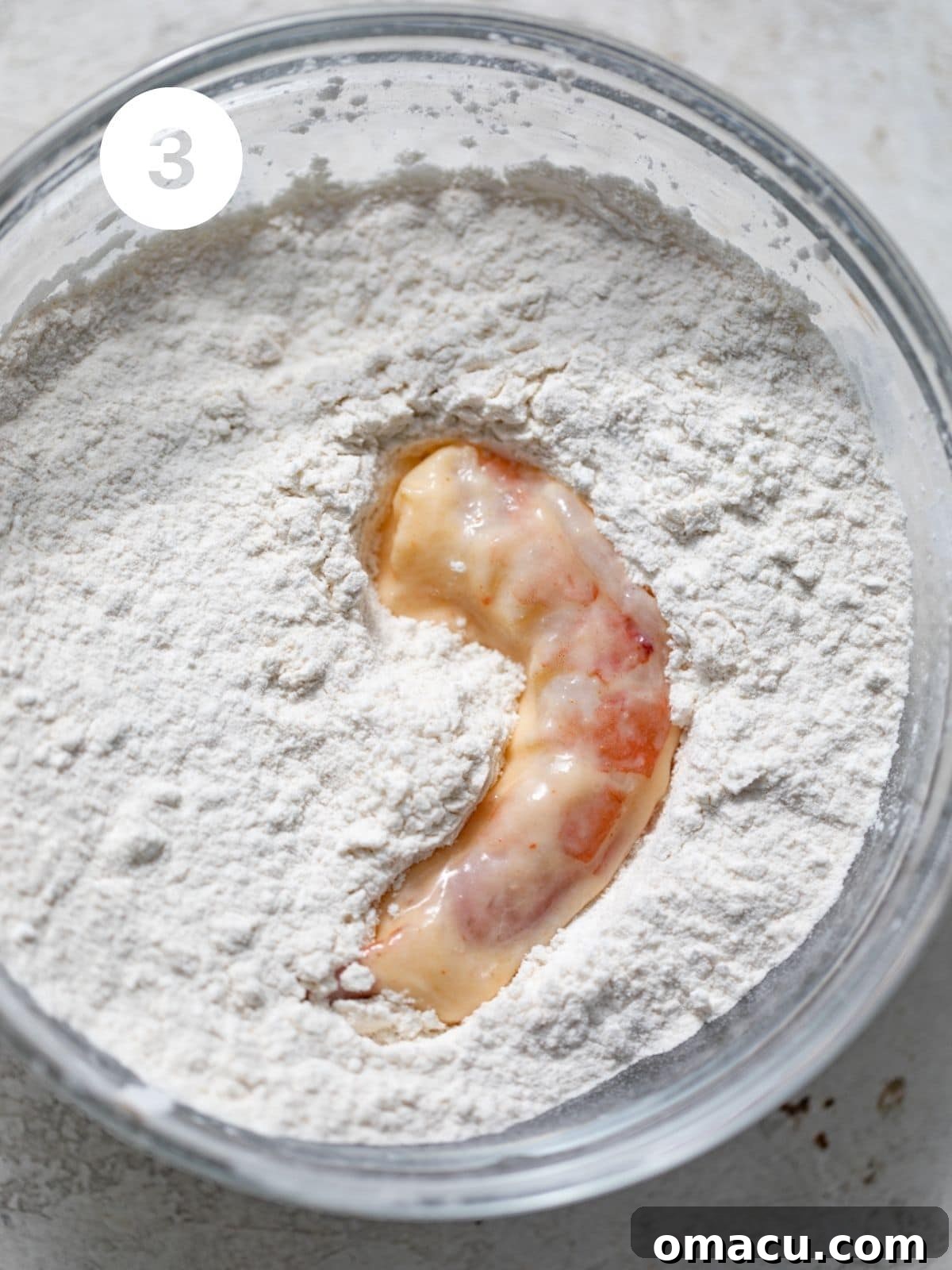Shrimp freshly coated in a dry breading mixture, showing a shaggy, textured surface ready for frying.