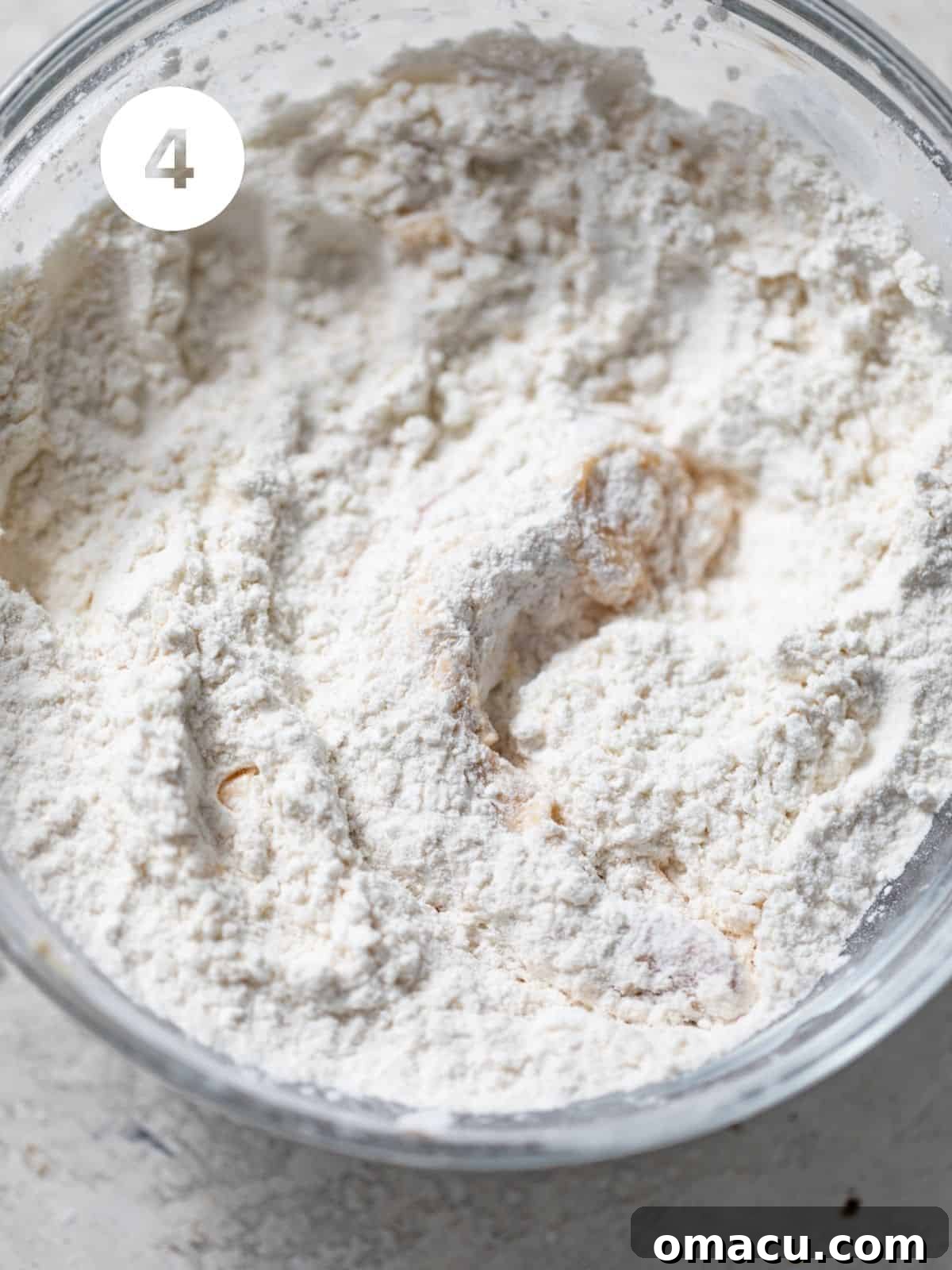 Shrimp being dredged in a bowl of flour and cornstarch mixture, ensuring full and even coating.