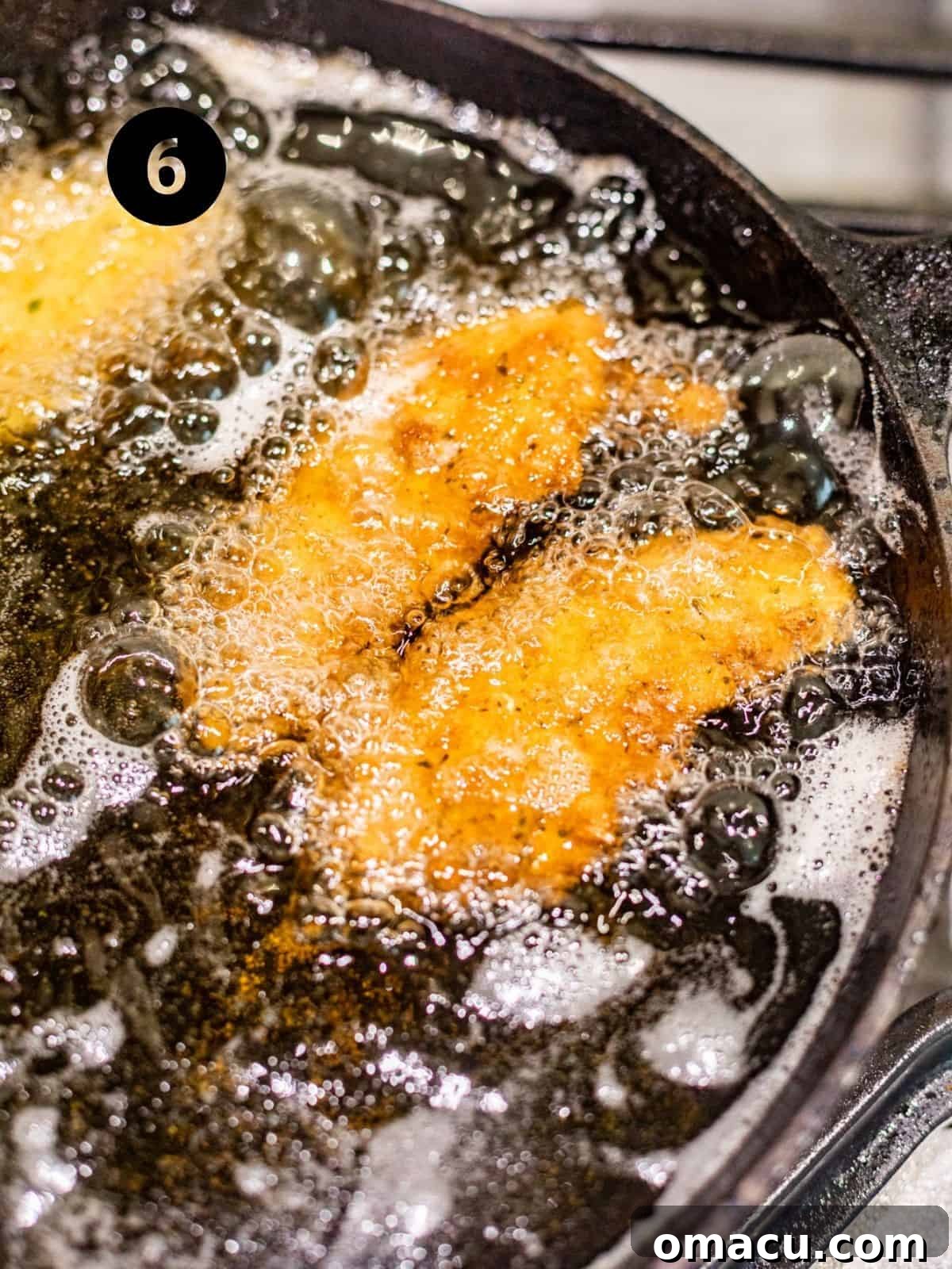 Shrimp frying in hot oil within a pan, bubbling vigorously as they turn golden brown and crispy.