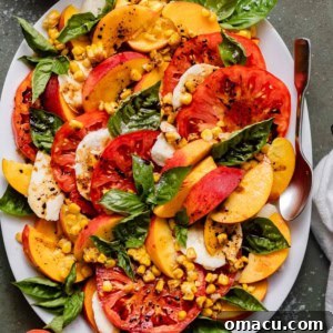 Close-up of a serving of Peach Caprese Salad with balsamic glaze and sea salt on a white plate, showcasing its fresh ingredients.