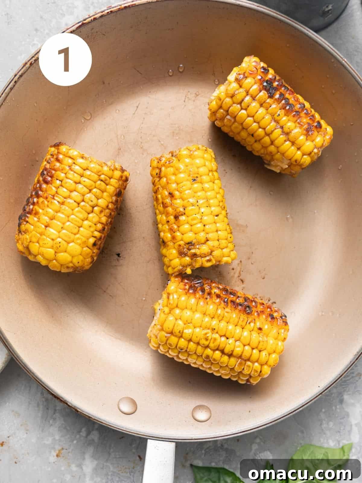 Close-up shot of sautéed corn kernels in a skillet, turning golden brown, illustrating the first step of making Peach Caprese Salad.
