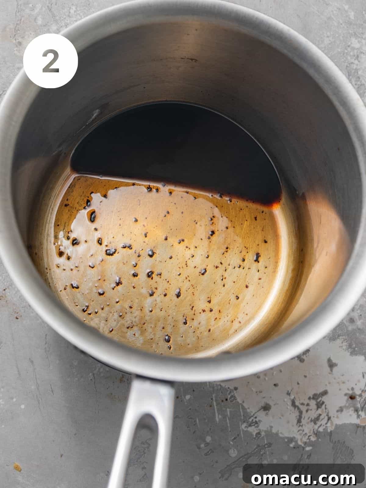 Balsamic glaze simmering in a small saucepan, indicating the reduction process to create a thick, glossy sauce for the Caprese salad.
