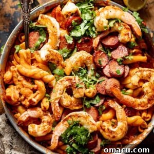 Cajun shrimp and sausage pasta in a skillet, garnished with fresh parsley.