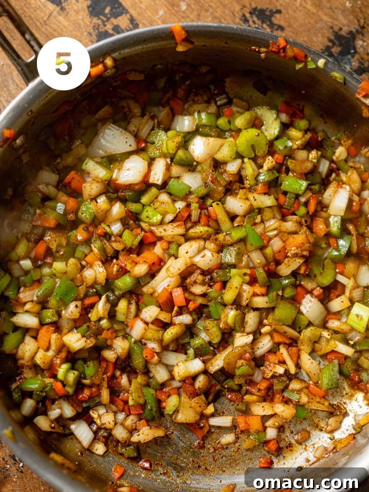 Diced onions, bell peppers, and celery, the Cajun Holy Trinity, sautéing in a pan with garlic.