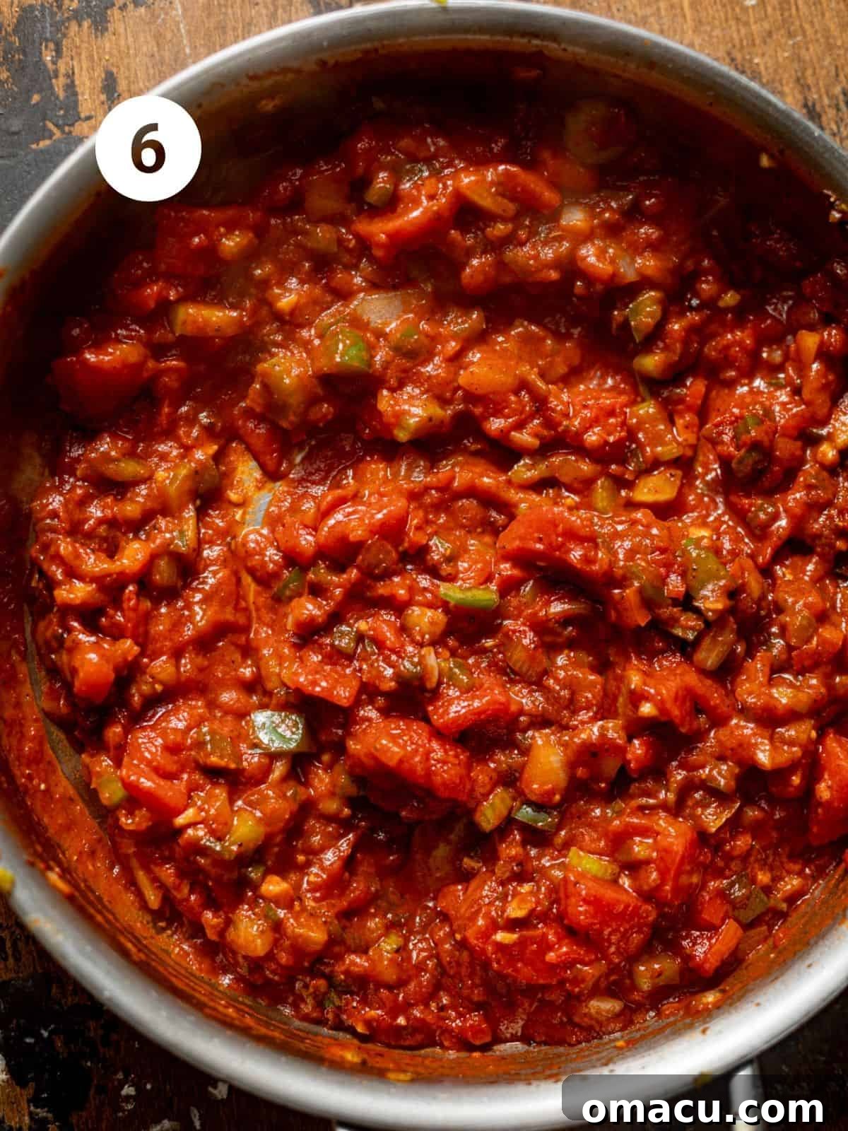 Creamy tomato sauce simmering in a pan with vegetables and spices.