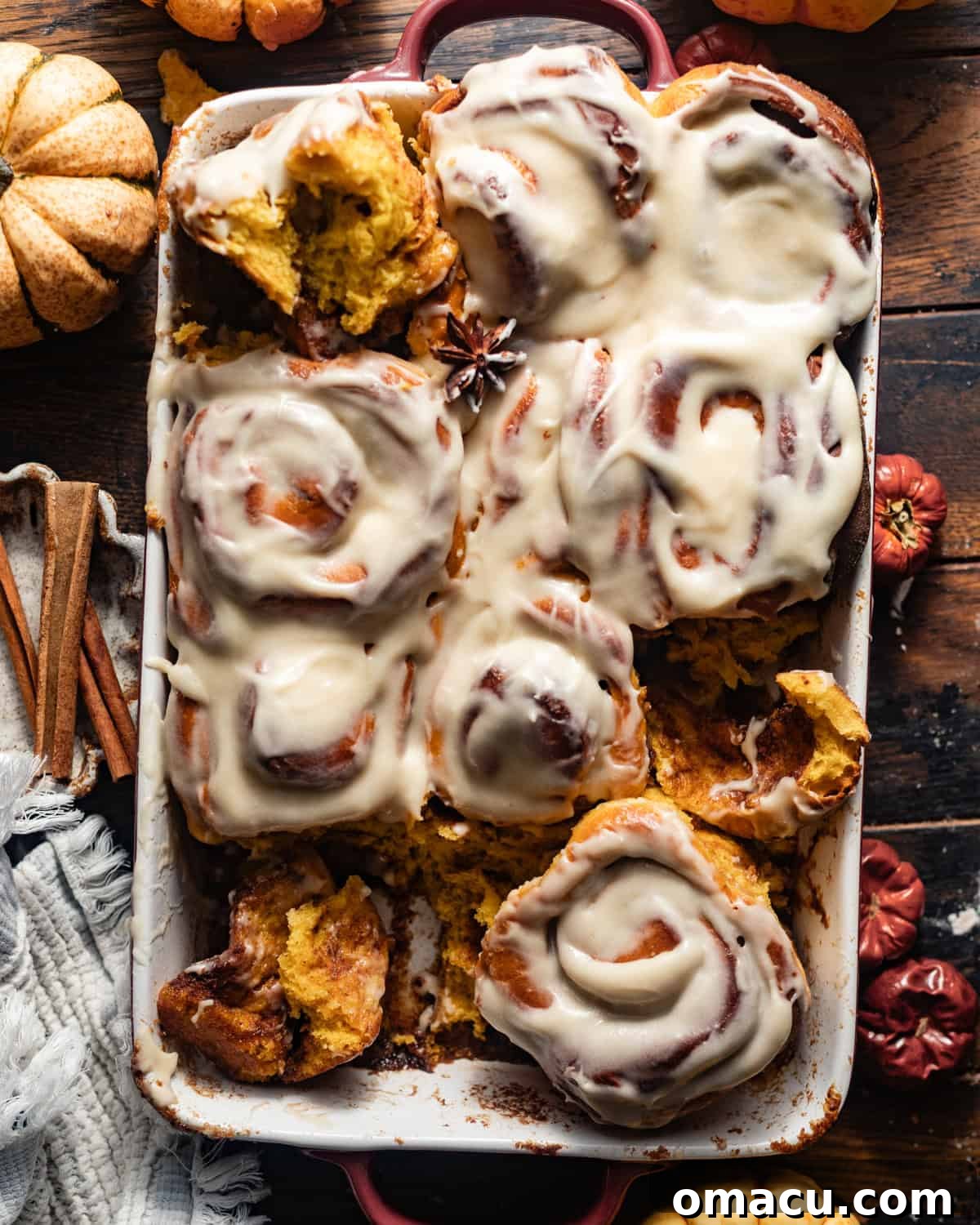 Overhead shot of freshly baked pumpkin cinnamon rolls in a baking dish, perfectly glazed and ready to be served.