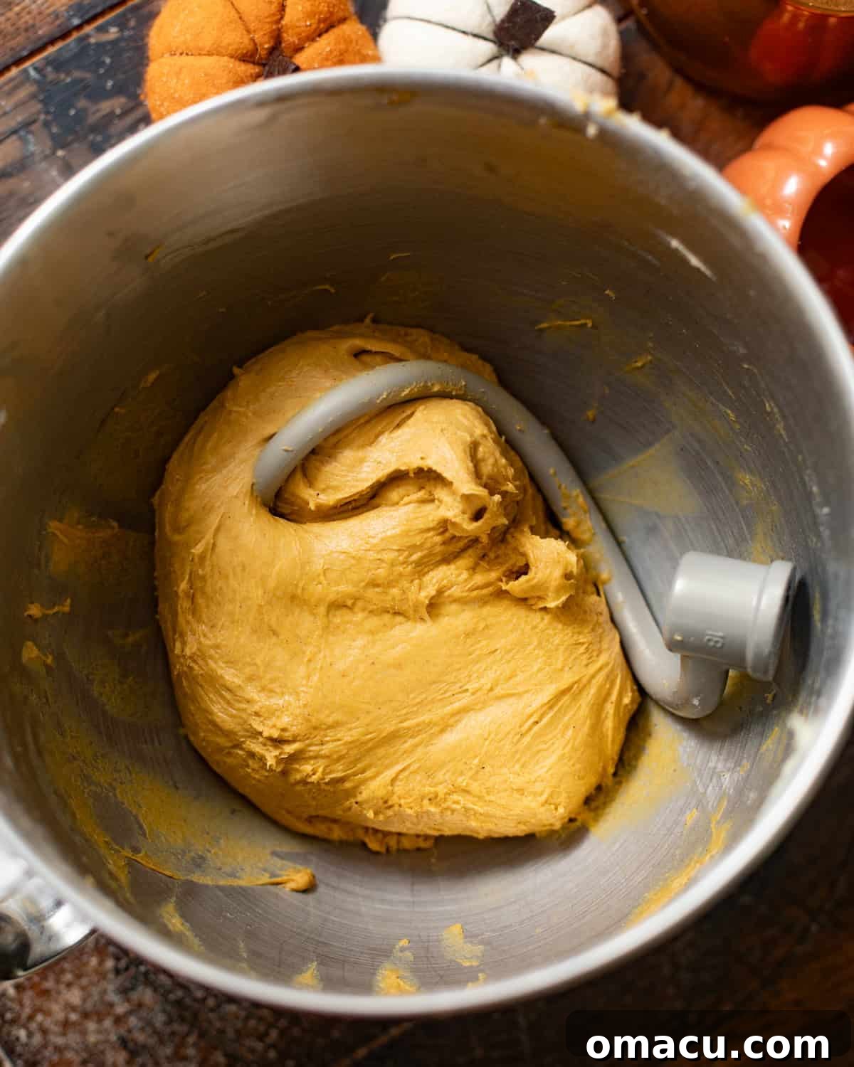 Dough in a stand mixer with the dough hook attachment, midway through kneading.