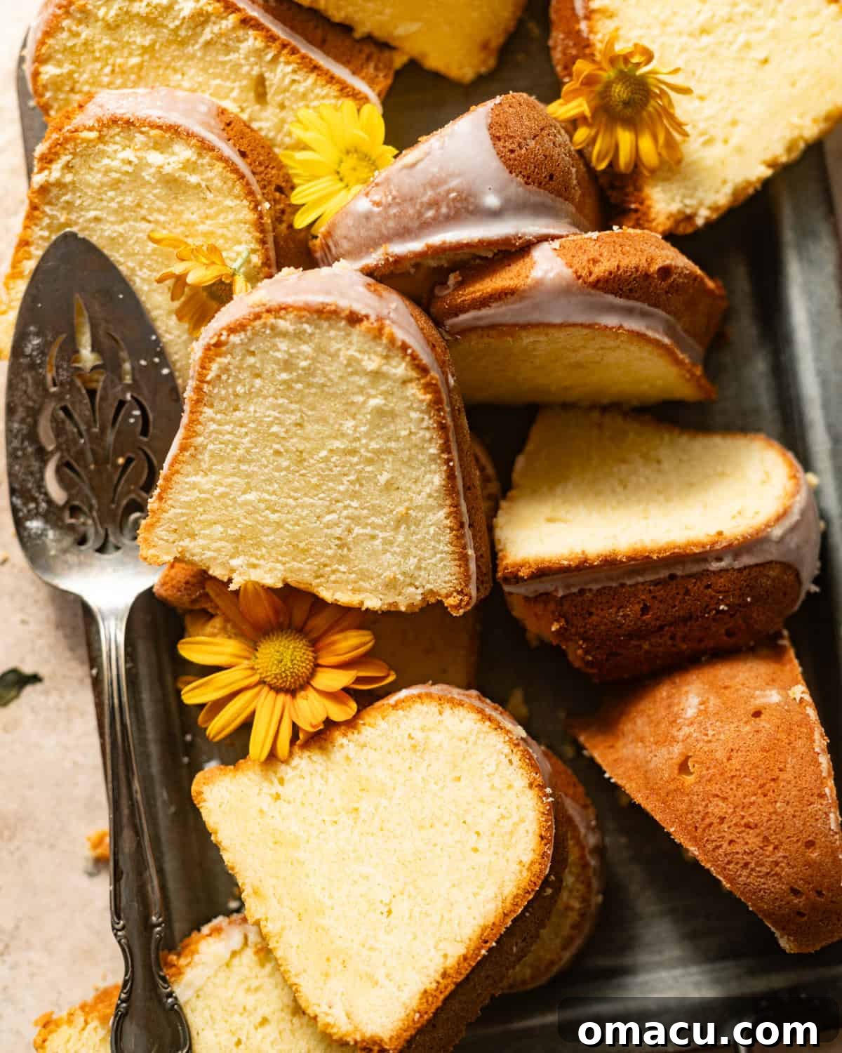 Beautifully sliced pieces of lemon cream cheese pound cake arranged on a serving tray, glistening with glaze.