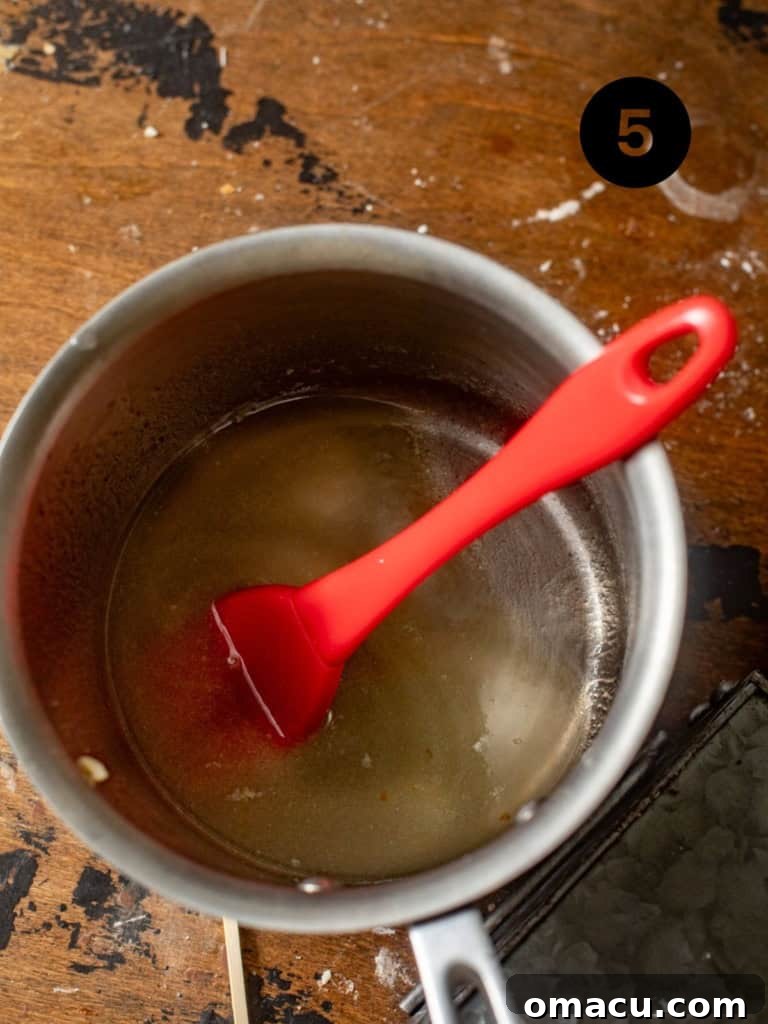 Lemon simple syrup simmering gently in a saucepan, ready to infuse the pound cake with flavor.