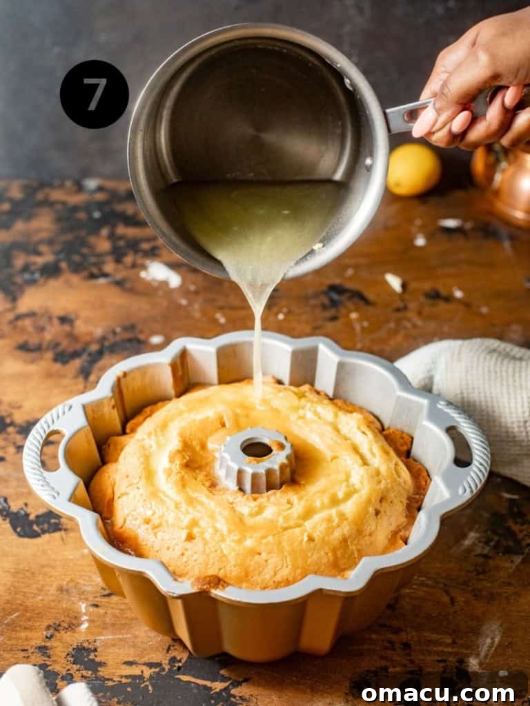 Pouring half of the warm lemon simple syrup onto the hot lemon cream cheese pound cake in the bundt pan.