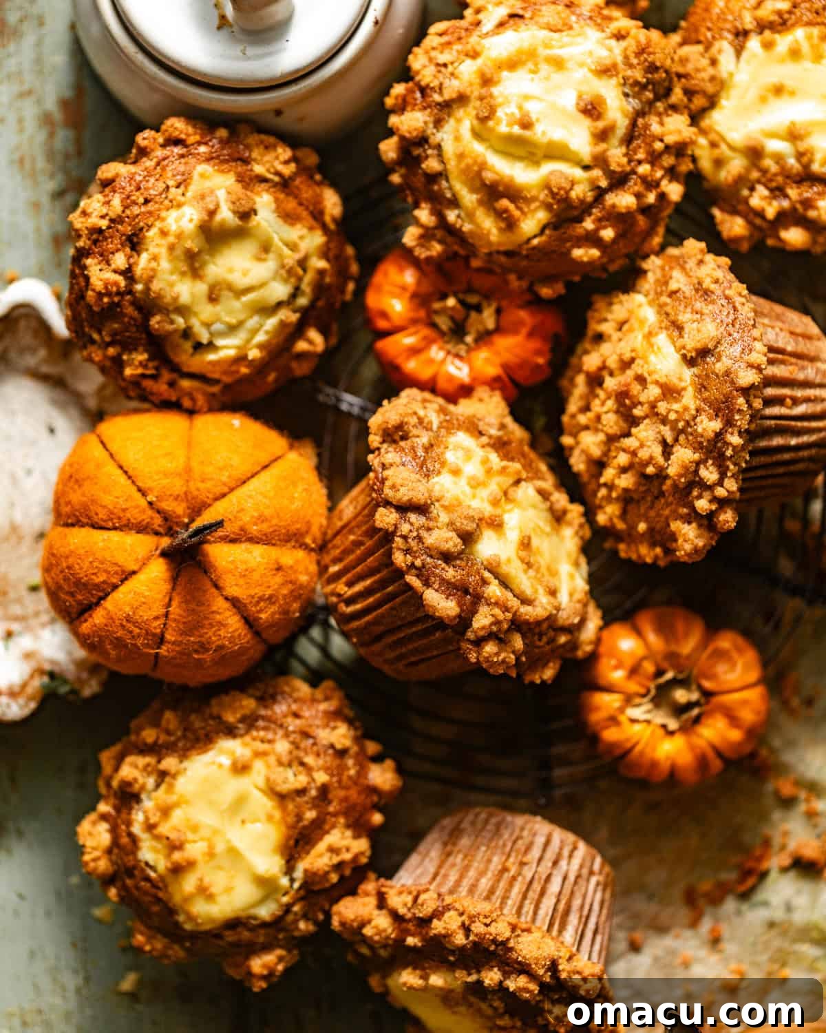 Delicious homemade pumpkin cream cheese muffins arranged on a rustic wooden table, surrounded by charming miniature pumpkins, creating a warm and inviting autumn scene.