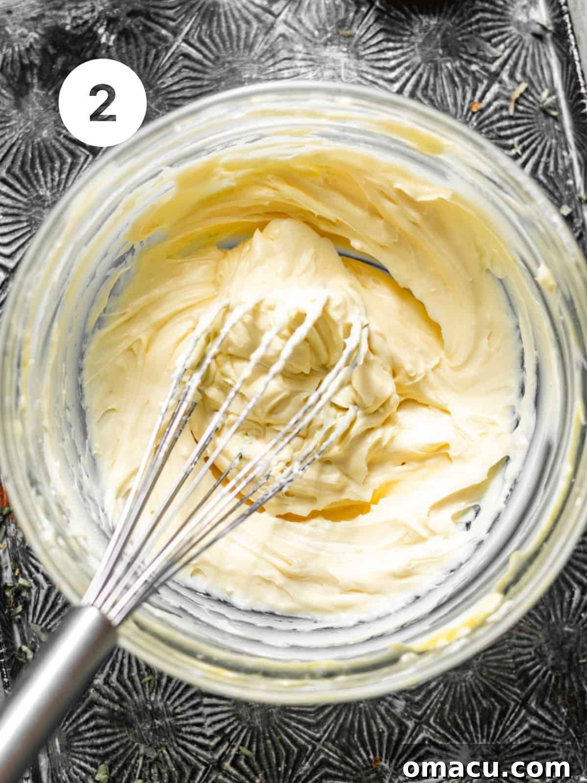 A smooth and fluffy cream cheese filling, expertly whisked together in a bowl, sits awaiting its role as a luxurious center for the pumpkin muffins.