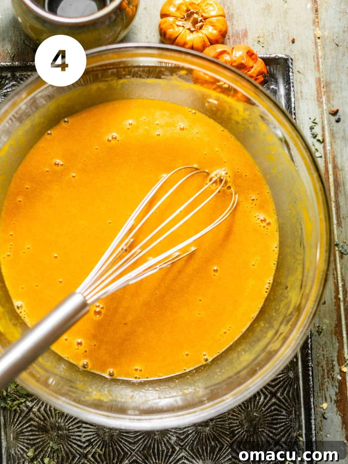 A separate bowl displays the carefully blended wet ingredients for the pumpkin muffins, featuring smooth pumpkin puree, eggs, brown sugar, granulated sugar, vegetable oil, sour cream, and vanilla extract.
