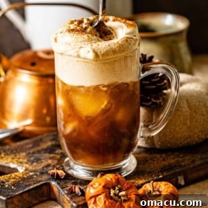 pumpkin cold foam in a cup with iced cold brew with a spoon stirring the cold foam into the cup.