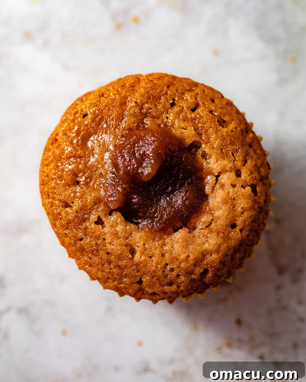An apple cider cupcake with its center cored out, showcasing the space ready to be filled with sweet apple butter.