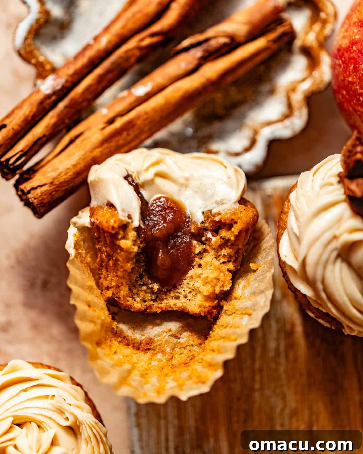 A perfectly baked apple cider cupcake, carefully sliced in half to reveal its rich, hidden apple butter filling.