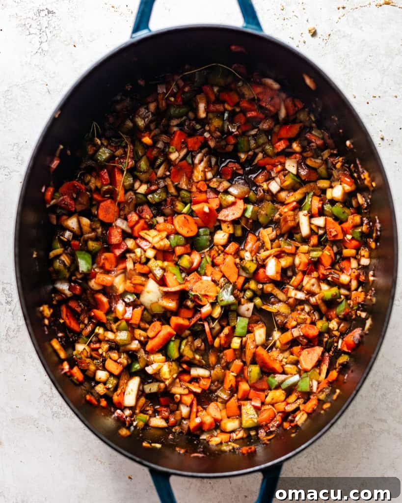The reserved chicken marinade, enriched with aromatic vegetables like carrots and ginger, gently sautéing in a skillet, building the flavorful base for the stew.
