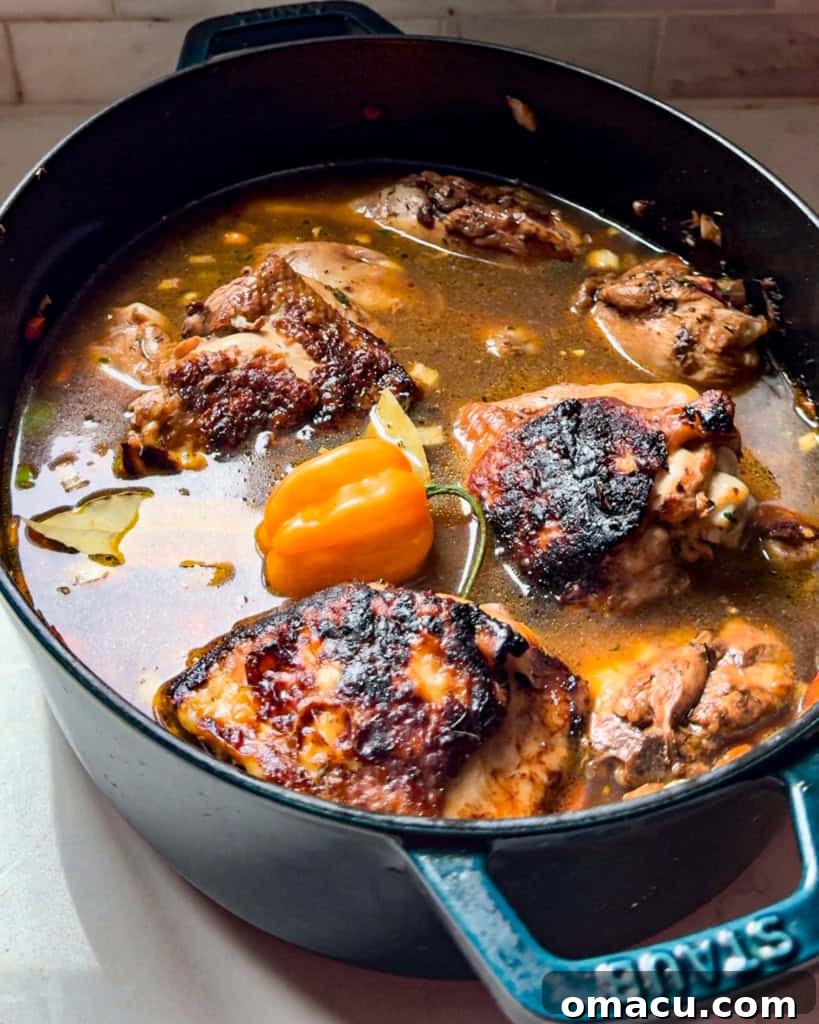 Tender brown stew chicken pieces immersed in a bubbling, rich brown gravy within a large pot, simmering to perfection.