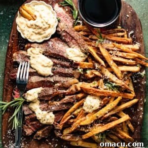 Steak frites on a cutting board with bearnaise sauce in a small bowl, showcasing the perfectly cooked steak and golden fries.