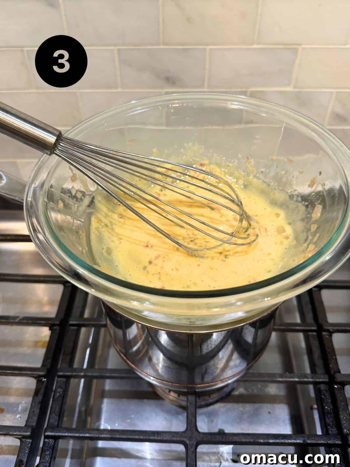 A glass bowl containing egg yolks, reduced vinegar, shallot, and tarragon, placed over a double boiler to thicken for béarnaise sauce.