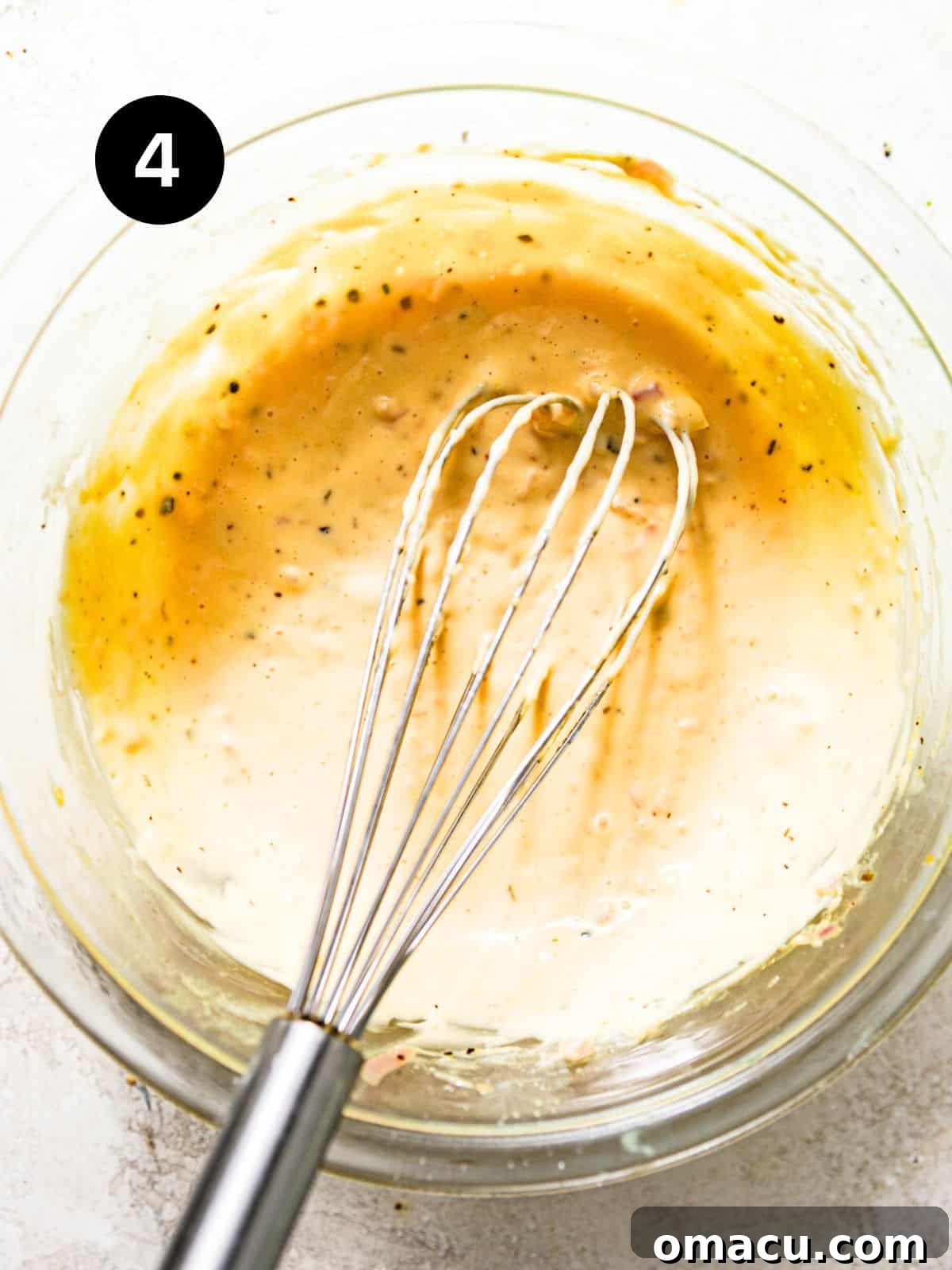 Smooth, creamy béarnaise sauce whisked together in a bowl, ready to serve.