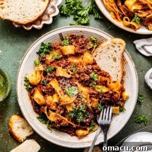 Short Rib Bolognese pasta in a bowl with bread and a fork.