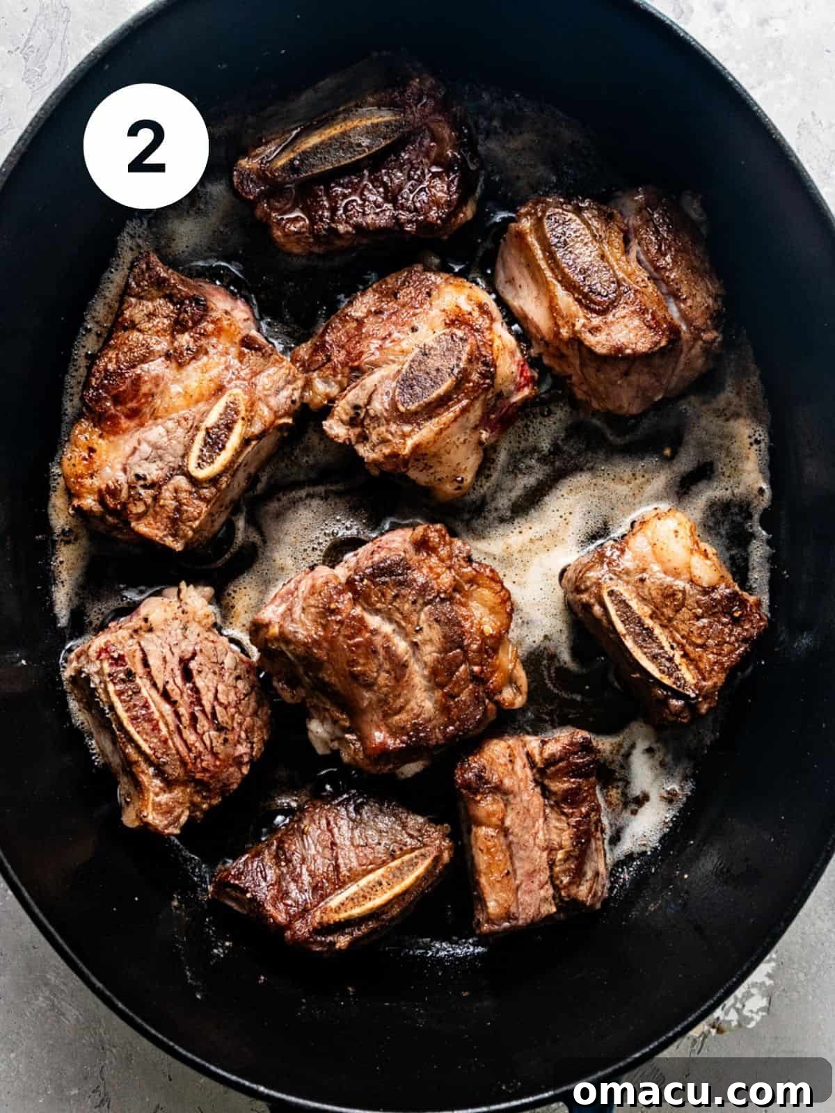 Short ribs searing to a golden brown in a large Dutch oven with melted butter and olive oil.