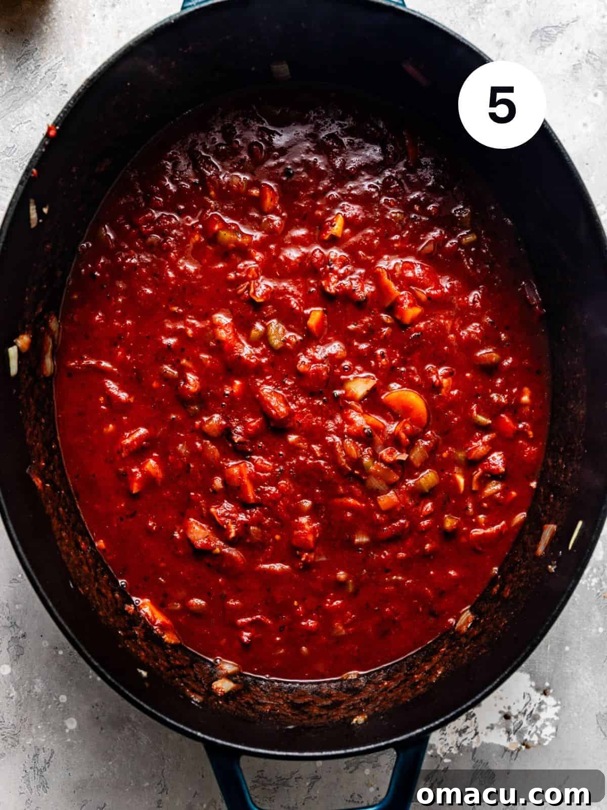 A rich ragu sauce simmering in a Dutch oven with the seared short ribs submerged, ready for braising.