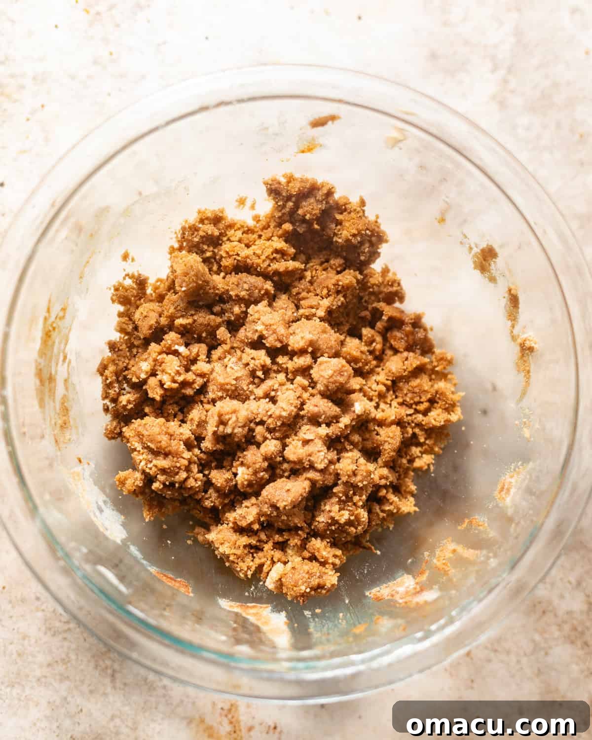 A bowl filled with cinnamon crumble topping, showing its distinct crumbly texture after being mixed.