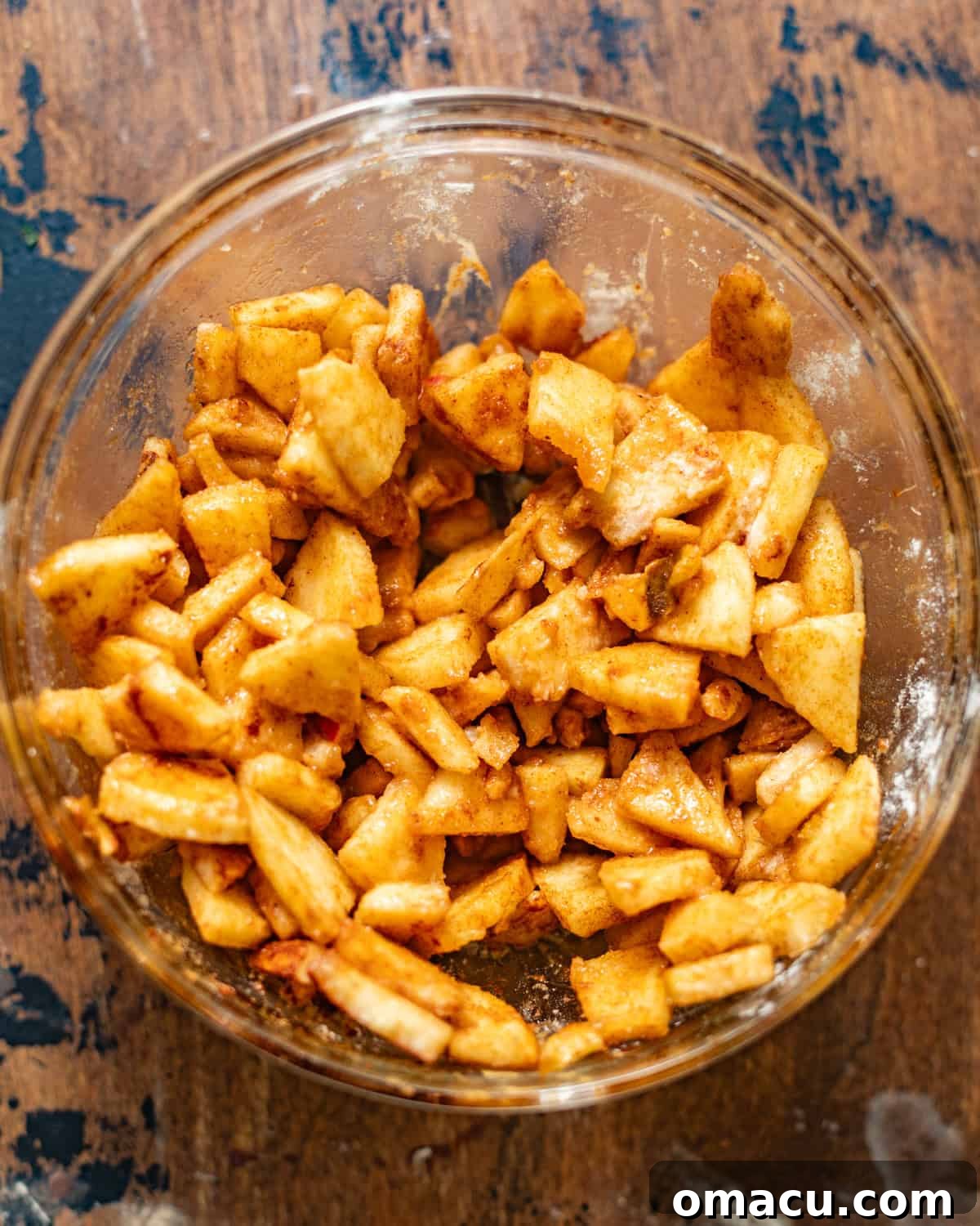Freshly sliced apples, coated evenly with cinnamon and sugar, ready to be incorporated into the cake batter.