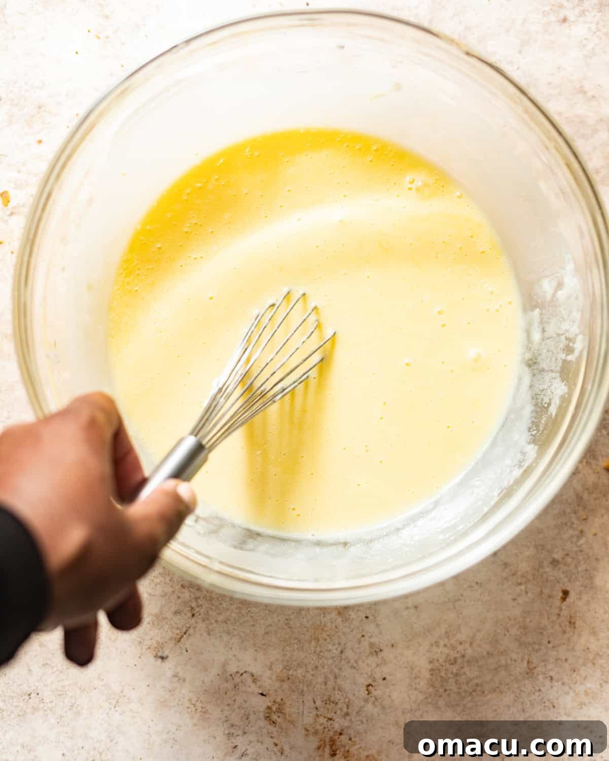 Wet ingredients, including sugar, oil, melted butter, vanilla extract, and eggs, whisked together smoothly in a large mixing bowl.