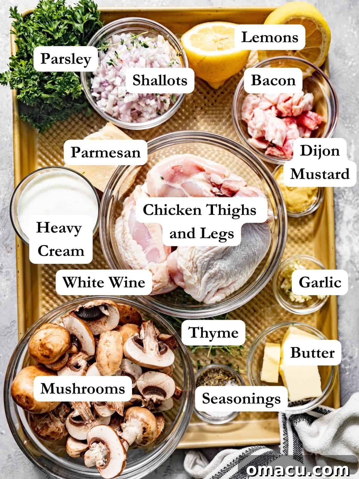 coq au vin blanc ingredients on a baking sheet - chicken, parsley, white wine, shallots, butter, olive oil, bacon, thyme, seasonings, heavy cream, lemon juice, garlic, and mushrooms.