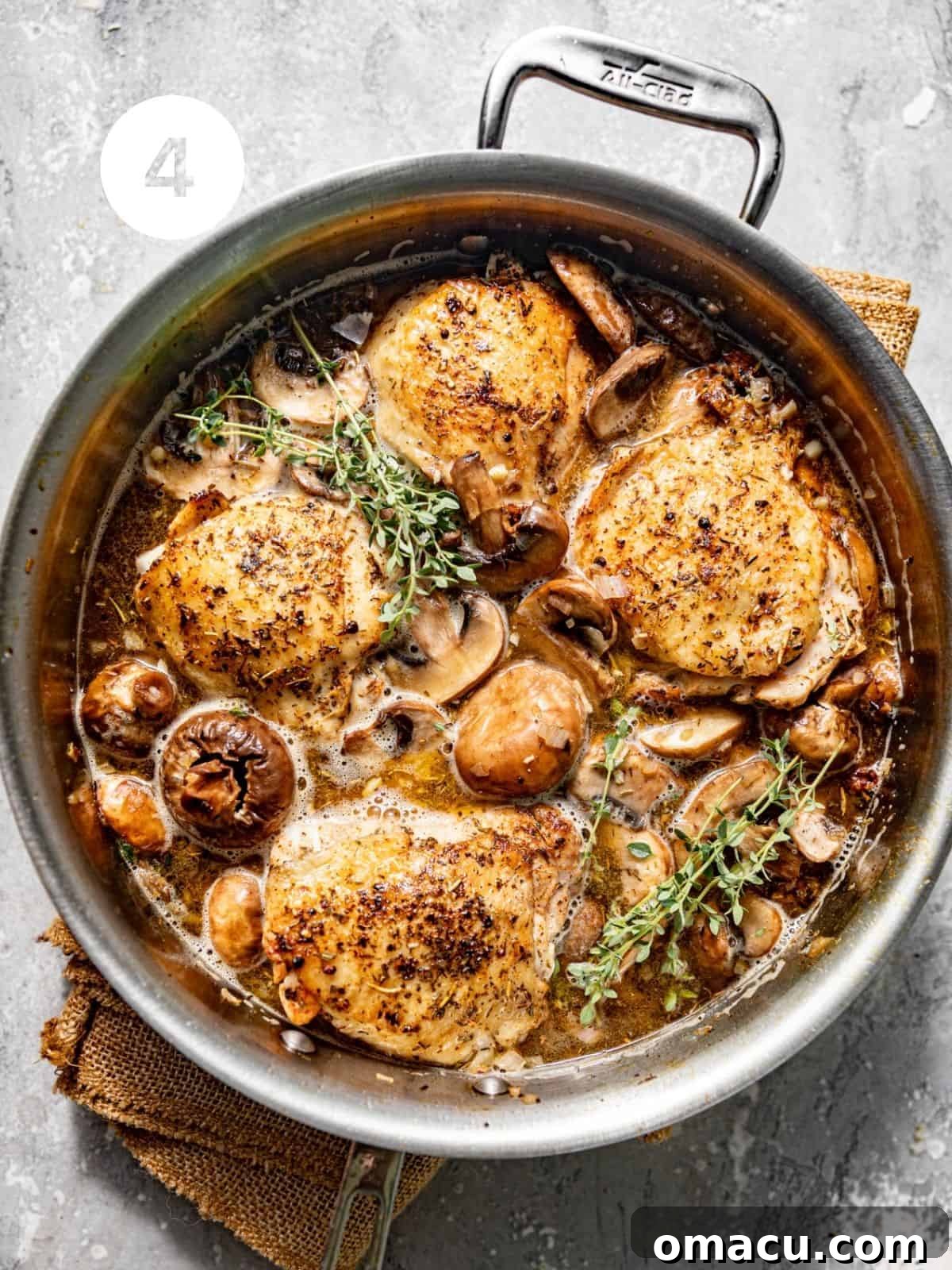 coq au vin in a skillet with white wine, herbs, and cream.
