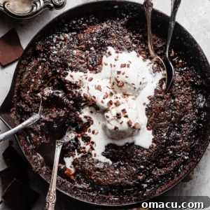 A delectable chocolate pudding cake in a skillet, adorned with melting ice cream and chocolate shavings.