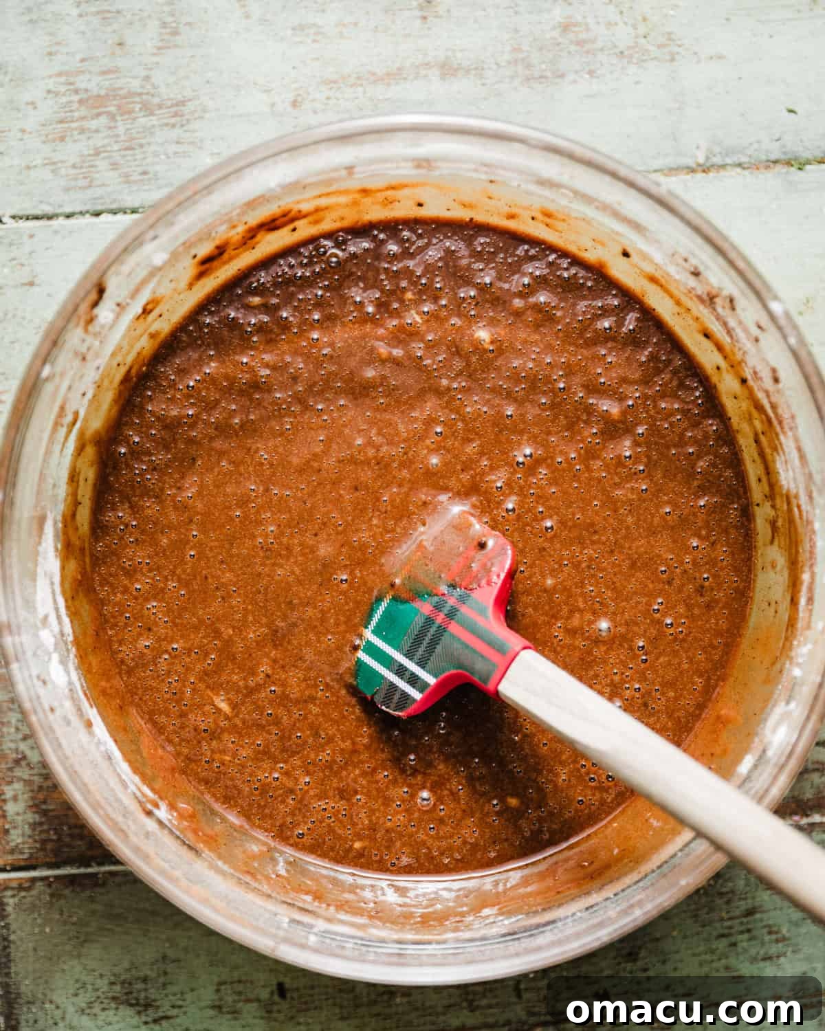 Smooth chocolate pudding cake batter, rich and dark, is whisked together in a mixing bowl, ready for the baking pan.