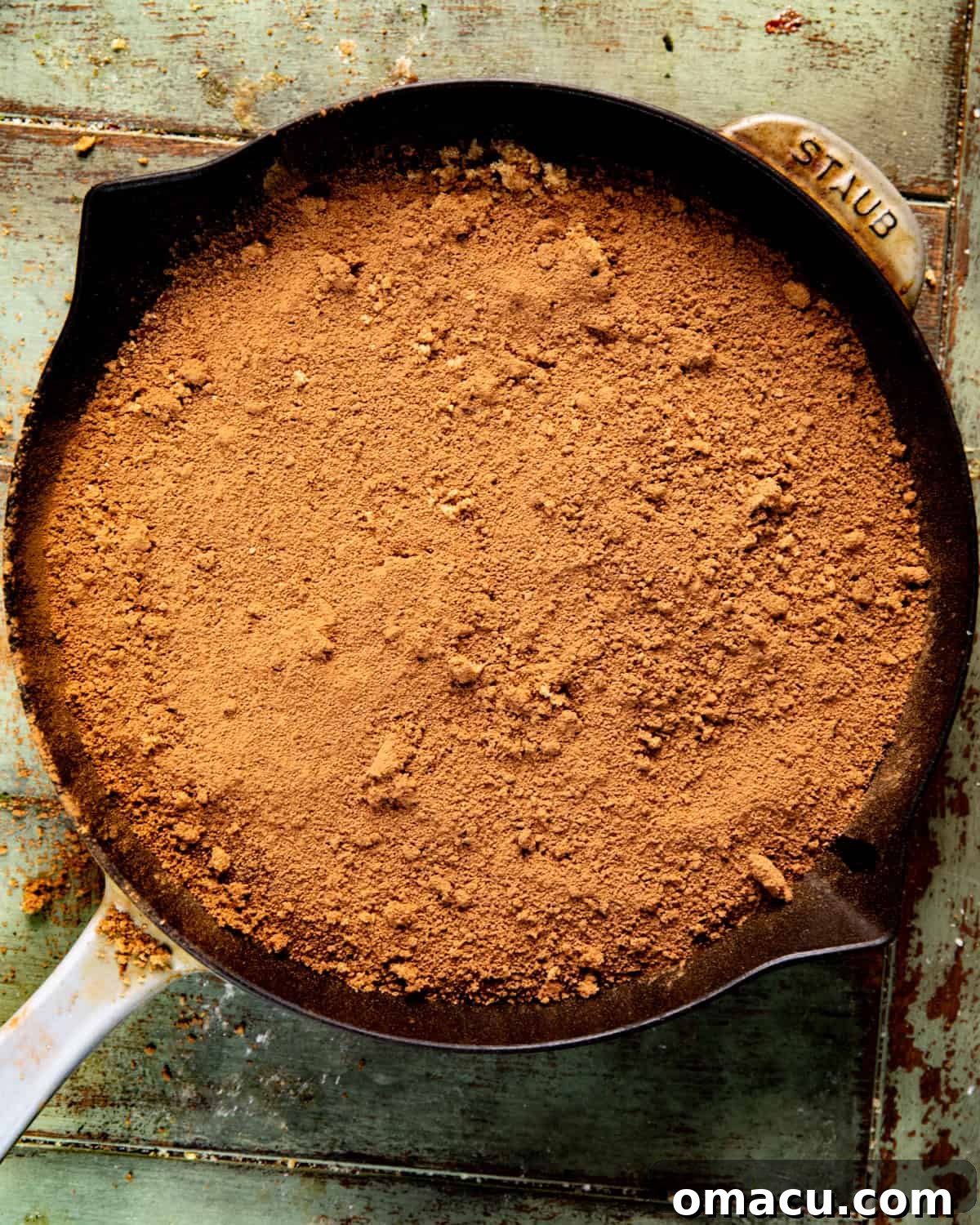 The chocolate pudding cake batter rests in a skillet, topped with an even layer of brown sugar and cocoa powder, ready for the hot liquid to be poured over.