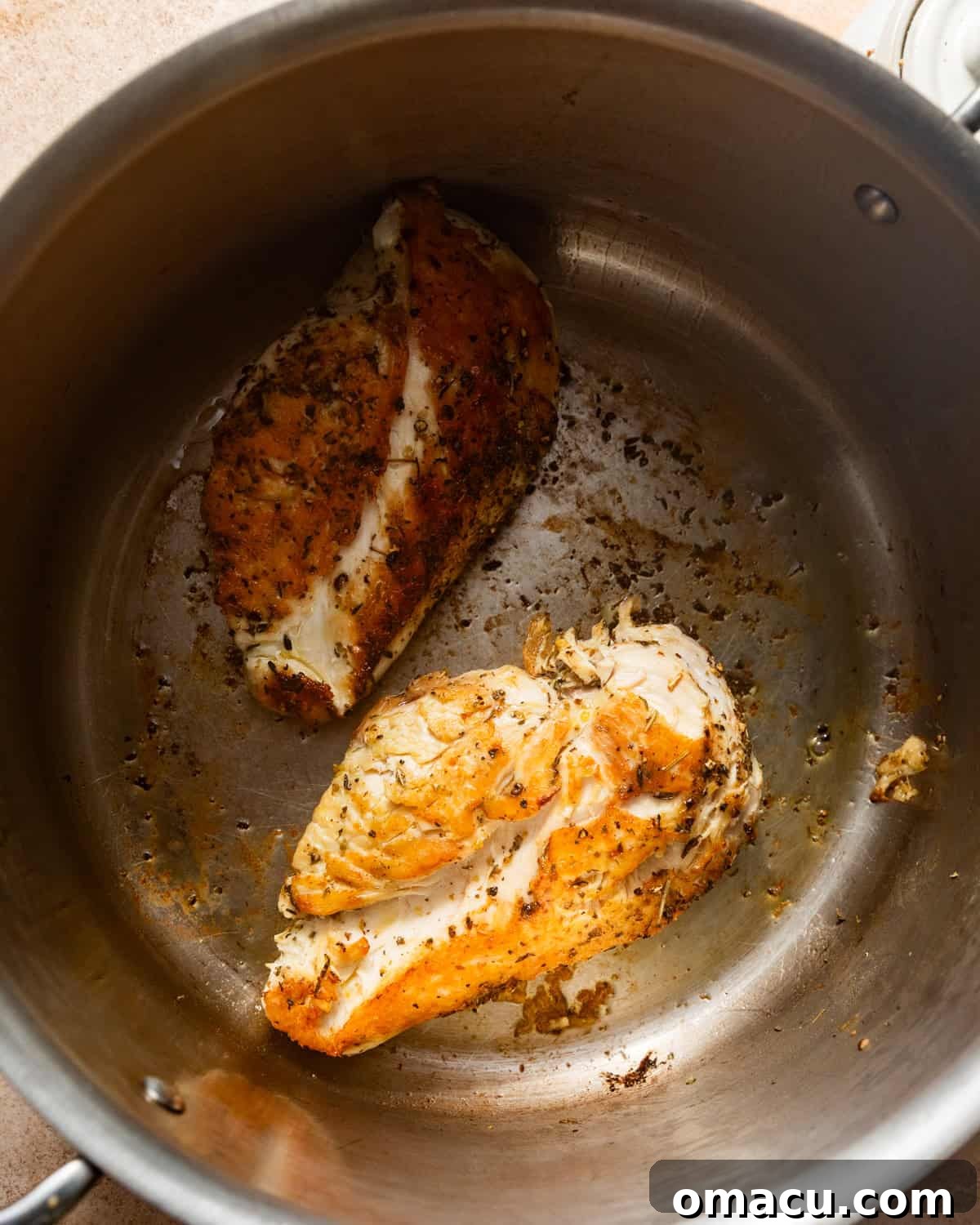 Seared chicken breasts in a large pot, golden brown and cooked through, ready to be removed.