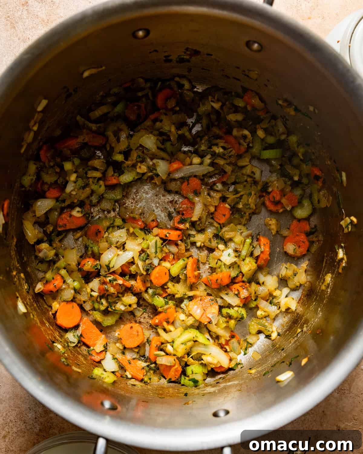 Sautéed carrots, celery, and onions in a pot, softened and fragrant, forming the aromatic base.